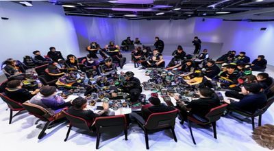 h游戏玩家社区线下聚会现场，玩家们围坐交流游戏心得，桌上摆放着各种游戏周边